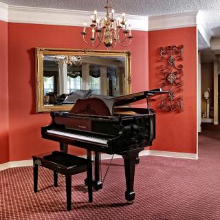 A grand piano in a living room with red walls and elegant decor.