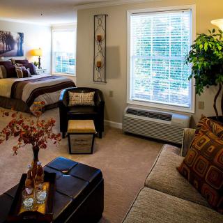 A cozy living and bedroom space with comfortable seating, warm lighting, and decorative elements.