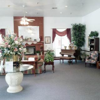 A cozy living room with elegant decor, featuring a fireplace, comfortable seating, and floral arrangements.