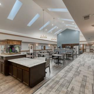 A modern dining area with skylights, featuring tables and chairs under elegant chandeliers.