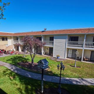 A two-story hotel building with a central courtyard and landscaped lawn.