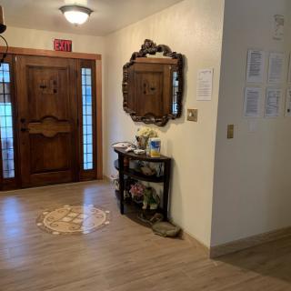 A cozy entryway with a wooden front door, accented by a decorative mirror and a small table.