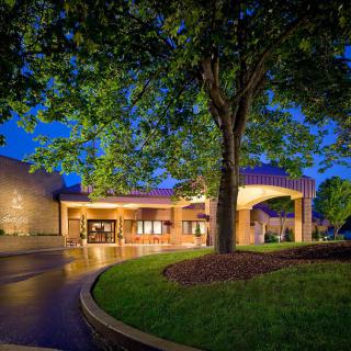 Illuminated building at night surrounded by trees and landscaping.