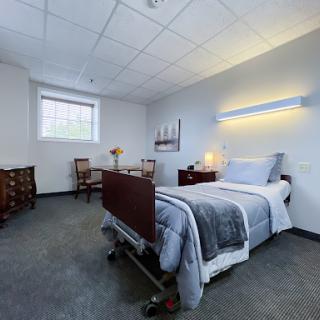 A well-lit hospital patient room featuring a bed, chairs, and a warm atmosphere.