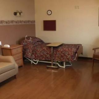 A hospital room with a bed, sofa, and chair.