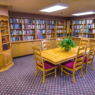 A cozy library room with wooden furniture and bookshelves filled with numerous books.