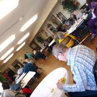A community gathering taking place indoors with people engaging in activities around tables.