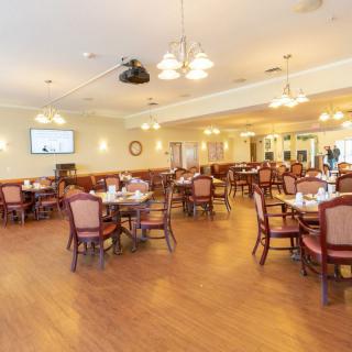An empty dining room with neatly arranged tables and chairs, illuminated by warm lighting.