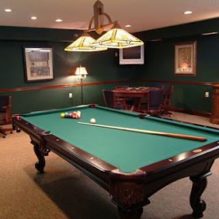 A cozy game room featuring a classic pool table with green felt and warm lighting.