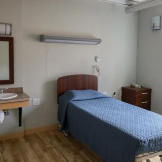 A clean hospital room with a single bed and medical equipment.
