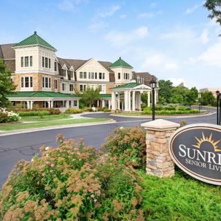 A scenic view of a residential building with a prominent entrance sign reading 'Sunrise'.