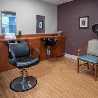 A modern hair salon showcasing a barber chair, wash station, and a comfortable waiting area.