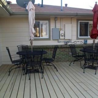 A patio deck with tables, chairs, and umbrellas.