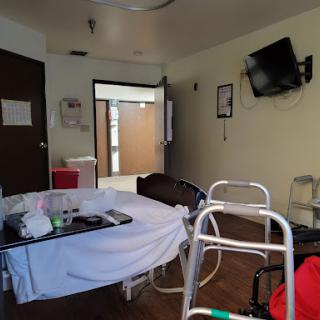 A hospital room equipped with a bed, walker, and television, conveying a clinical atmosphere.