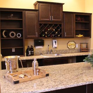 A stylish modern kitchen featuring dark cabinetry and a granite countertop, complete with wine storage.