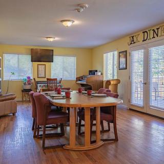 A cozy dining room with a large wooden table and chairs, featuring abundant natural light from surrounding windows.