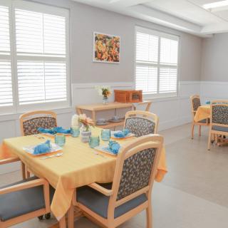 A bright dining room with neatly set tables and comfortable chairs.
