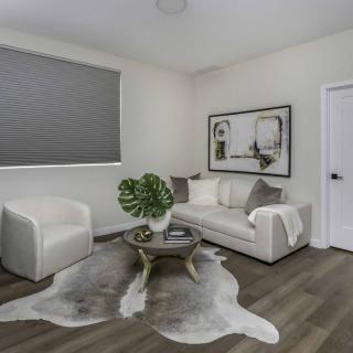 A modern and minimalist living room with a white sofa, armchair, coffee table, and indoor plant.