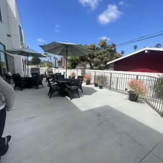 A spacious outdoor patio area with black furniture and umbrellas, perfect for enjoying a sunny day.
