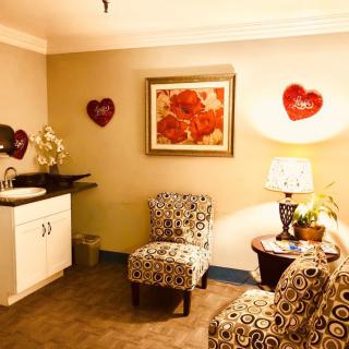 A cozy waiting room with patterned chairs, heart decorations, and a warm lamp.