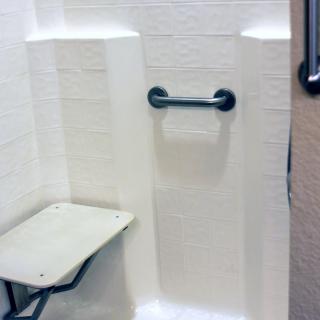 An accessible shower with a grab bar and folding seat for enhanced safety.
