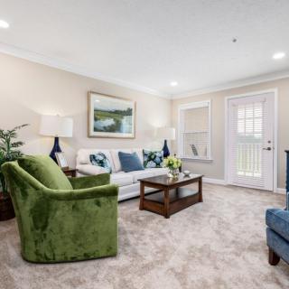 A modern living room featuring a green armchair, plush sofa, and elegant decor.