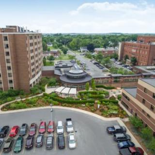 Aerial view of a hospital complex with surrounding buildings and a parking lot.