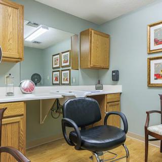 A hair salon interior with a styling chair, mirror, and wooden cabinets.