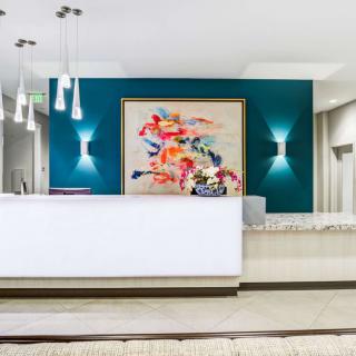 A modern lobby with a reception desk and abstract art displayed on the wall.