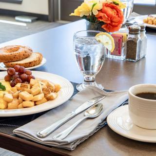 A breakfast spread featuring a plate of fruit and pastry, coffee, and water.