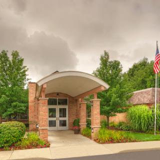 The welcoming entrance of a community building, framed by lush greenery and a flag.