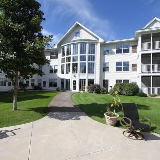 A sunny day view of a multi-story residential building with well-maintained landscaping.