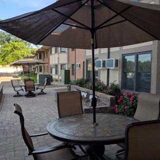 Outdoor patio area with tables, chairs, and umbrellas near a building.