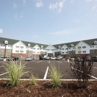 A large residential or commercial building with a spacious parking lot, surrounded by landscaped greenery.