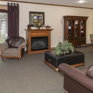 A cozy living room interior with a fireplace, armchairs, couch, and decorative elements.