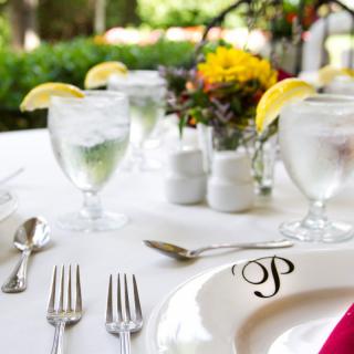 A beautifully arranged outdoor table set for a formal dining experience, featuring elegant glassware and floral decorations.