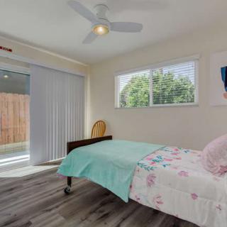 A minimalist bedroom with a single bed, large window, and sliding glass door.