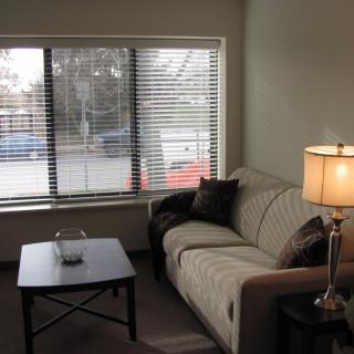 A cozy living room with a sofa, lamp, and coffee table near a window.