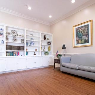 A modern living room with white bookshelves, a couch, and framed artwork on the wall.
