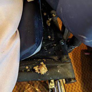 A messy airplane seat with food spill.
