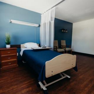A clean and minimalist hospital room with a single bed and wooden flooring.