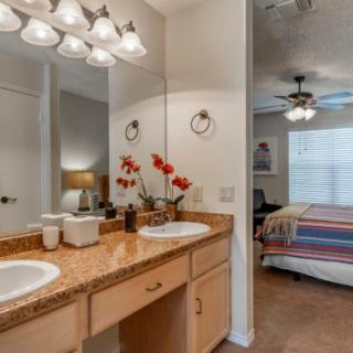 A cozy home interior featuring a bathroom with double sinks and an adjoining bedroom.