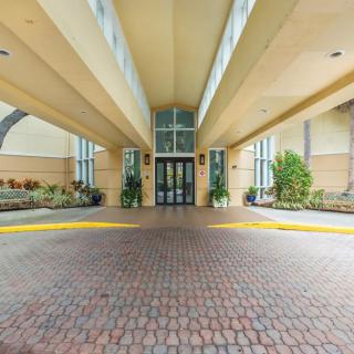 The image shows the entrance of a hotel featuring modern architecture and landscaping.