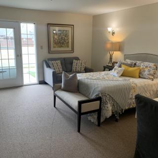 A cozy bedroom with modern decor, featuring a bed, sofa, and ample natural light.