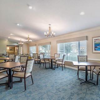 A spacious dining area with several tables and chairs, featuring large windows and modern chandeliers.