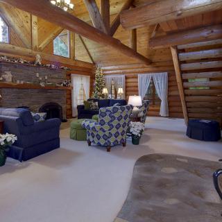 A cozy log cabin living room with rustic wooden beams and a fireplace.