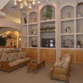 A cozy lounge area featuring wicker furniture, decorative shelves, and elegant lighting.