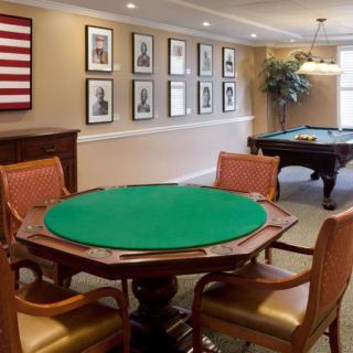 A cozy game room featuring a poker table and billiards area with elegant decor and seating.