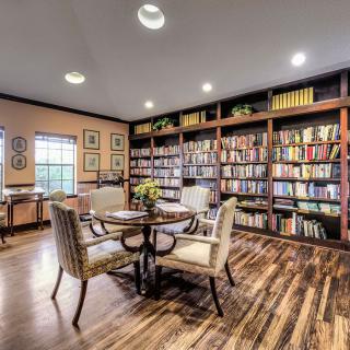A cozy library room with bookshelves, a reading table, and chairs.