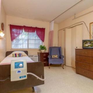 A cozy hospital room with a bed, comfortable chair, and television.